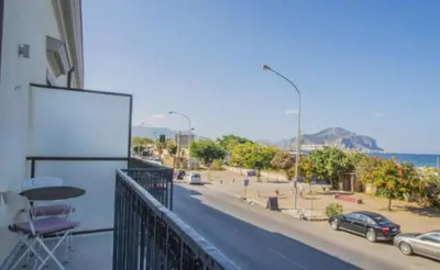 a balcony of a building with a table and a street at Casa Gelsomino POOL&SEAVIEW in Palermo