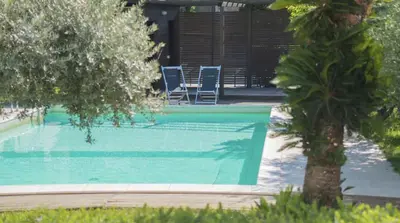 a swimming pool with two chairs and a tree at Casa Gelsomino POOL&SEAVIEW in Palermo