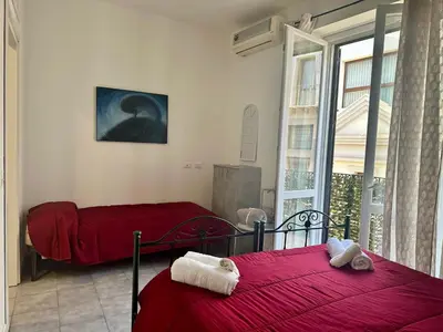 a bedroom with two beds with red sheets and a window at Maqueda Vibes in Palermo