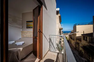 an open door to a balcony with a bed at Casa vacanza la finestra sul porto in Castellammare del Golfo