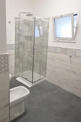 a bathroom with a shower and a toilet and a window at Da 'Nfacci Affittacamere in Carini