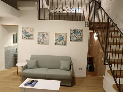 a living room with a couch and a staircase at IGIEA APARTMENT in Palermo