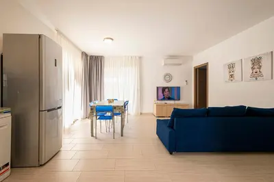 a living room with a blue couch and a kitchen at Borgo Aranci - Villa Unifamiliare Ibiscus 08 in Castellammare del Golfo