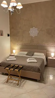 a bedroom with a large bed and a table at Mona House accogliente casa vacanza in Palermo
