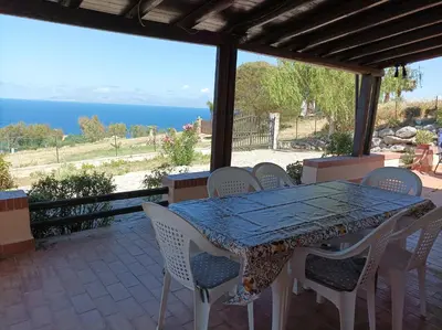 a table and chairs on a patio with a view of the ocean at La Terrazza su Pispisa in Castellammare del Golfo