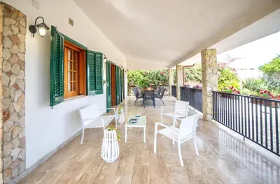 a patio with white chairs and tables on a balcony at Villa Reyna in Scopello