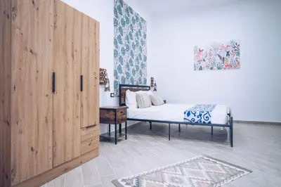 a bedroom with a white bed with a blue and white wallpaper at Scorcio di Mare By Dimora Hub in Balestrate