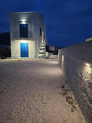 a white house with a blue door and a wall at Un Posto Al Sole in San Vito lo Capo