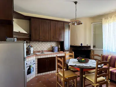 a kitchen with a table and chairs and a refrigerator at Le Casette di Campagna in Campofelice di Roccella
