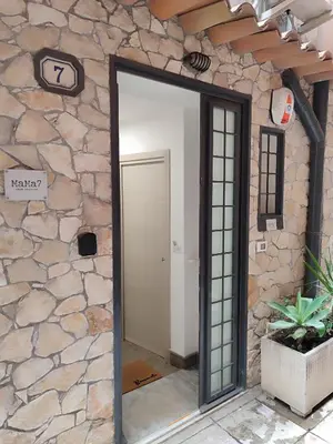 a door into a room with a stone wall at MaMa7 in Palermo