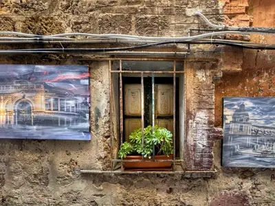 a window with two potted plants on a stone building at MaMa5 in Palermo