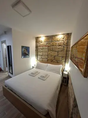 a bedroom with a large white bed with a stone wall at MaMa5 in Palermo