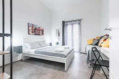 a white bedroom with a bed and a window at GuestHost - Palazzo dei Normanni & Ballarò Roomy Modern Apt x9 in Palermo
