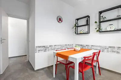 a dining room with a white table and two red chairs at GuestHost - Palazzo dei Normanni & Ballarò Roomy Modern Apt x9 in Palermo