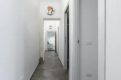 a hallway with white walls and a tile floor at GuestHost - Palazzo dei Normanni & Ballarò Roomy Modern Apt x9 in Palermo