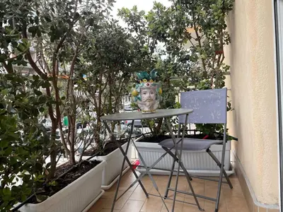 a table and a chair on a balcony with trees at Lazio apartment nel centro di Palermo in Palermo