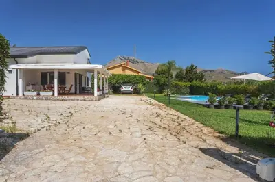 a house with a stone driveway leading to a pool at Villa NìMia in Castellammare del Golfo