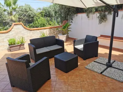 a patio with four chairs and an umbrella at Holiday House Nonna Grazia in Trappeto