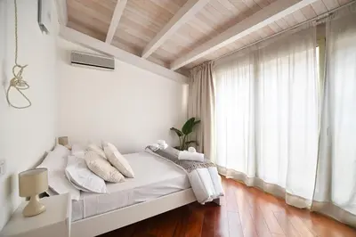 a white bedroom with a bed and a large window at iFlat Casa Viscuttara in Palermo
