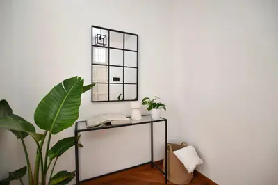 a mirror on a white wall next to a table with a plant at iFlat Casa Viscuttara in Palermo