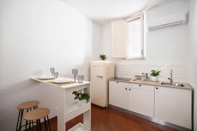 a white kitchen with a refrigerator and a table at iFlat Casa Viscuttara in Palermo