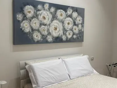 a bedroom with a bed with a painting on the wall at Lily Suite in Palermo