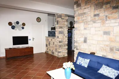 a living room with a blue couch and a stone wall at Villa Maruzza (Sicilia Bedda) in Carini