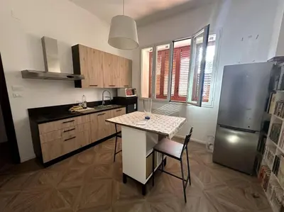 a kitchen with a table and a refrigerator at Casa Vacanza Mondello in Palermo