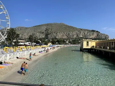 a beach with a ferris wheel and people in the water at Casa Vacanza Mondello in Palermo