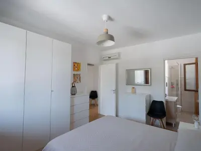 a white bedroom with a white bed and a desk at Villa Kamarà in Castellammare del Golfo
