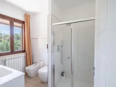 a white bathroom with a shower and a toilet at Villa Kamarà in Castellammare del Golfo