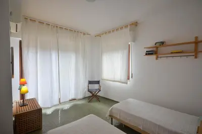a bedroom with two beds and a chair next to a window at Casa Garofani in Carini