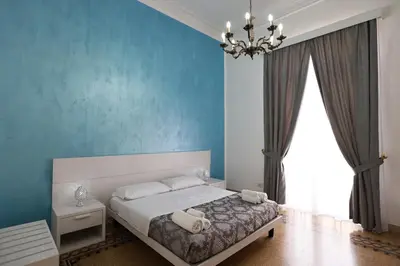 a bedroom with a bed with blue walls and a chandelier at Il Siciliano room’s & suite in Palermo
