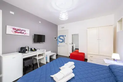 a bedroom with a blue bed and a desk with a computer at Il Vittoria - Self Check in in Lascari