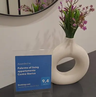 a white vase with flowers in it next to a sign at Palermo of living appartamento Centro Storico in Palermo