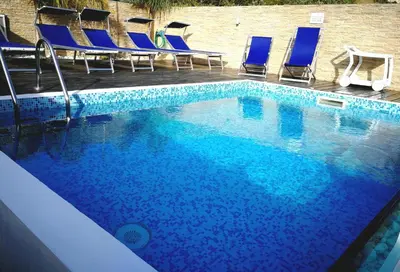 a large swimming pool with blue chairs in a hotel at B&B Il Sole in Castelluzzo