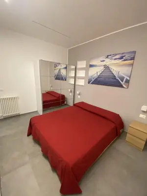 a bedroom with a red bed and a painting on the wall at Casa Penelope in Mondello