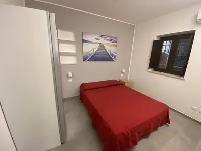 a bedroom with a red bed and a window at Casa Penelope in Mondello