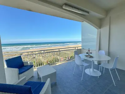 a balcony with a table and chairs and the beach at La perla sulla spiaggia in Alcamo Marina