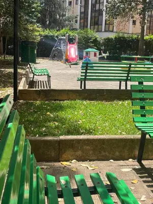 a park with green park benches and a playground at Claudio House Palermo in Palermo