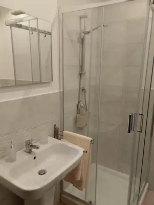 a white bathroom with a sink and a shower at Appartamento centro storico(Nina's house stazione) in Palermo