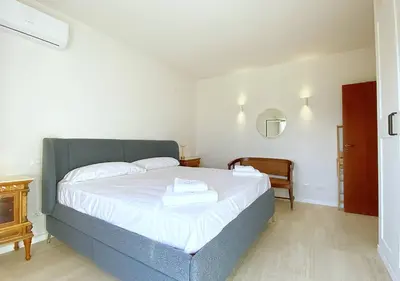 a bedroom with a bed with white sheets and a mirror at Solemar Sicilia - Casa Tosca in Ficarazzi