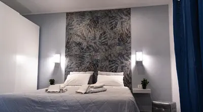 a bedroom with a large bed with a wall at NIKA NIKA Holiday House in Carini
