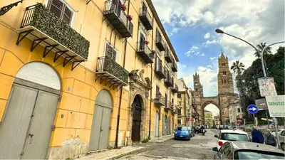a street with cars parked next to buildings and a church at Residenza Cattedrale in Palermo