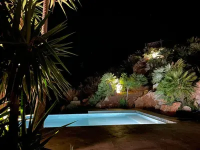 a swimming pool in the middle of a garden at night at QUIETE e MARE in San Vito lo Capo