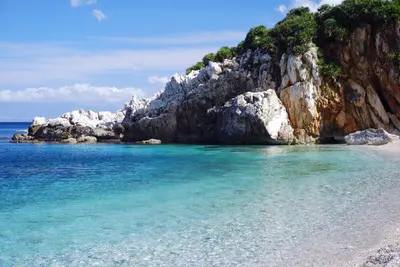 a beach with blue water and rocks in the ocean at Villa Francesca in Castelluzzo