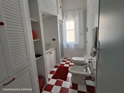 a white bathroom with two toilets and a sink at Casa Vacanze Zafarana in Santa Flavia