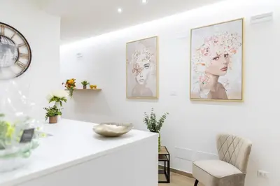 a white room with paintings on the wall and a chair at ARIA b&b in Terrasini