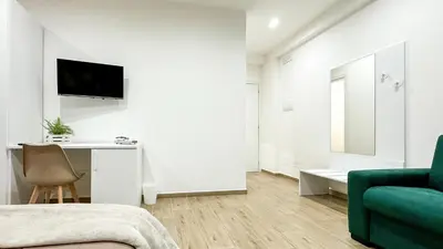 a white bedroom with a green couch and a desk at ARIA b&b in Terrasini