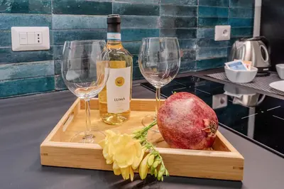 a bottle of wine and two wine glasses on a cutting board at Trabia25 Suite Palermo in Palermo